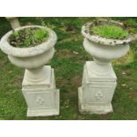A pair of painted and weathered cast composition stone garden urns with circular lobed bowls and