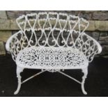 A small cream painted cast iron garden seat with decorative repeating open scroll pattern, 94cm wide