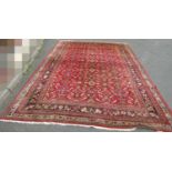 A large country house Persian design Rug, hand-knotted with repeated floral pattern on a red ground,