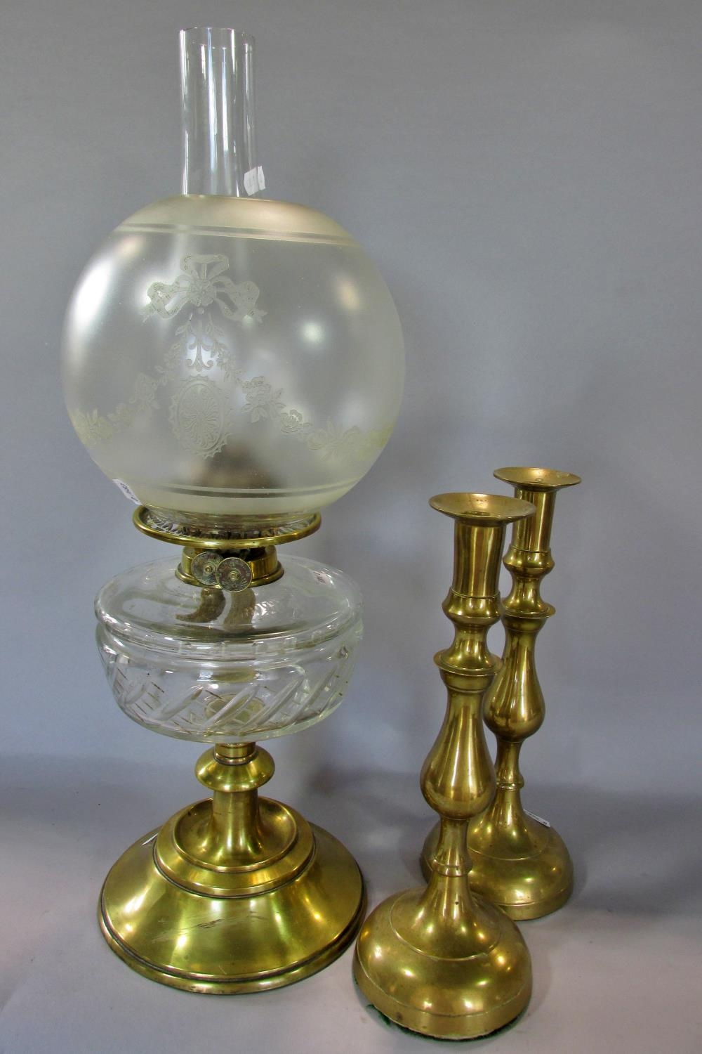 A Victorian brass oil lamp on a spread foot, with clear glass font and frosted garland decorated