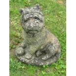A weathered cast composition stone garden ornament in the form of a seated terrier with ball sat