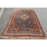 An old Persian hand-knotted rug with central stepped medallion on a predominantly blue ground,