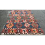 An old Kilim with rows of multicoloured diamond hooked medallions on a red ground, 260cm x 170cm