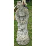 A weathered cast composition stone garden ornament in the form of a maiden releasing a dove, 85cm