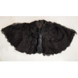 A late 19th / early 20th century shoulder cape in black patterned fabric overlaid with lace and