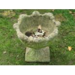 A weathered cast composition stone garden urn with circular acanthus leaf bowl, raised on a loose