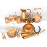 A mixed collection of copperware including hunting horns, kettles, jugs, graduated grain measures,