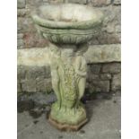 A weathered cast composition stone Three Graces birdbath with classical circular egg and tongue
