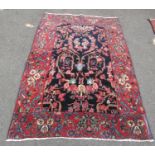 A Persian rug with all-over floral design, visible areas of repair and restitching, in dark blue and