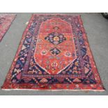 A Persian rug with central medallion and flower and branch motifs, in dark red, orange and navy