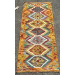 A Chobi Kilim runner with a row of six multicoloured medallions enclosed in a geometric pattern