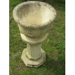 A weathered cast composition stone garden urn of circular tapered form with fixed ring and floral