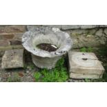A weathered carved natural stone garden urn of circular form with flared rim and lobed body, (af)