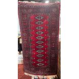 A Princess Bokhara design rug with eleven central lozenges on a crimson ground, 95 x 180 cm