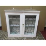 A painted pine wall cupboard with leaded light doors