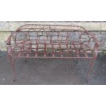 A weathered ironwork two seat garden bench with strapwork seat, twisted rails, and open arched back,