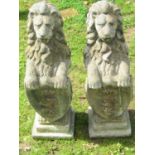A pair of weathered cast composition stone garden terrace or pier ornaments in the form of lions