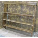 A stripped pine country made wall rack with three fixed shelves flanked by chamfered and moulded