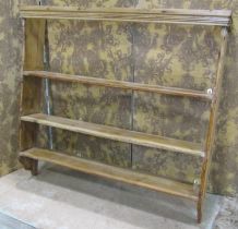 A stripped pine country made wall rack with three fixed shelves flanked by chamfered and moulded