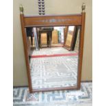 A mahogany wall mirror of simple form with pewter inlaid detail, surmounted by two brass urn