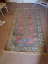 An eastern wool rug, with triple medallion centre upon a pink field, set within running geometric