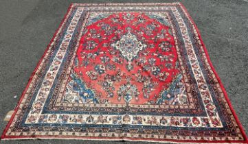 A large countryhouse Malayer type carpet with an all over floral pattern on a red ground (af worn in
