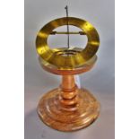 A small contemporary desk top brass sun dial on a turned wooden base, labelled to underside 'by John