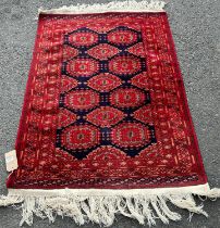 A Bokhara rug with a field of ten red guls on a blue ground with geometric borders, 150cm x 100cm