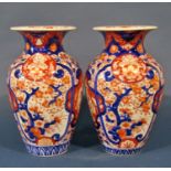 A pair of 19th century Imari vases in a red and blue colourway with repeating geometric detail, 32cm