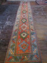 A long wool runner with ten medallion centre, upon a brick red field within geometric running