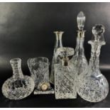 A square diamond cut decanter with a silver collar, four further decanters, a cut glass water jug