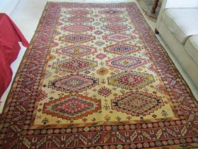 An eastern wool rug with beige field, with sixteen lozenge shaped medallions, further geometric