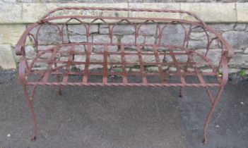 A weathered ironwork two seat garden bench with strapwork seat, twisted rails, and open arched back,