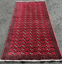 A Turkoman carpet with an all over small gold design on a red ground, 205cm x 100cm approx