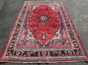 A Malaya style carpet with a central medallion on a red ground with a field of flowers, 290cm x