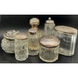 Assorted dressing table scent bottles, jars and a nail buffer, etc, most with silver lids or caps,