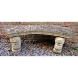 A weathered three section composition stone garden bench with crescent shaped seat raised on