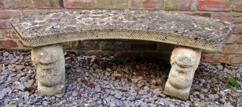 A weathered three section composition stone garden bench with crescent shaped seat raised on