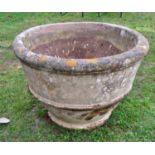 A large weathered composition stone garden planter of circular tapered ribbed form, 87cm diameter