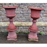 A pair of faux terracotta cast composition stone garden urns of classical design with flared rims,
