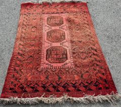 A Bokhara rug with a central row of three elephant foot gul on a faded red ground, 190cm x 134cm