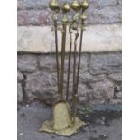A cast brass fireside companion set with claw and ball pommels and scrolling tray base, (af)
