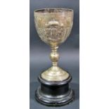 A silver metal chalice engraved with several English quotations and heraldic beasts, raised on a