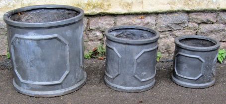 A graduated set of three weathered faux lead squat cylindrical planters the largest example 46cm