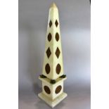 A marble obelisk ornament with marble inlaid shapes resting on the backs of four Verdigris