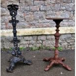 Two weathered vintage cast iron pub table bases of varying size and design, the largest 86cm high