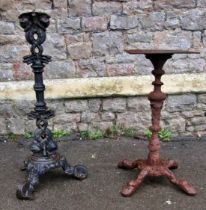 Two weathered vintage cast iron pub table bases of varying size and design, the largest 86cm high