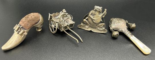 A collection of miniature silver items including a frog playing the mandolin, a menu holder, a small