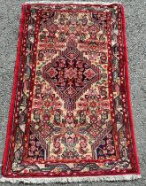 A small Kasak type rug with a central medallion in reds oranges and blues, 130cm x 80cm