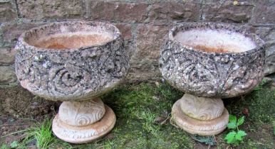 A pair of weathered cast composition stone garden urns, the squat circular bowls with repeating